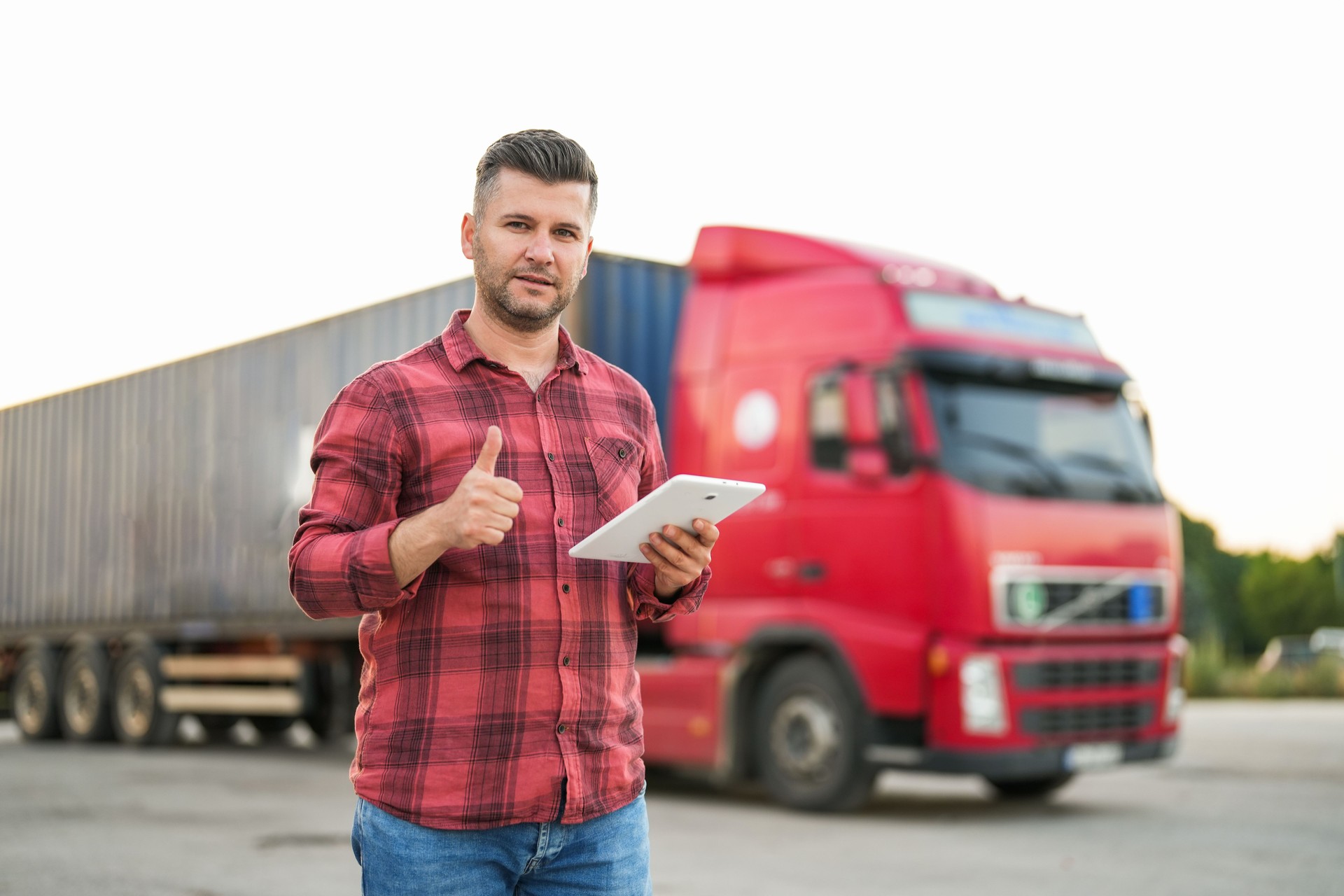 man looking at his tablet in front of red truck