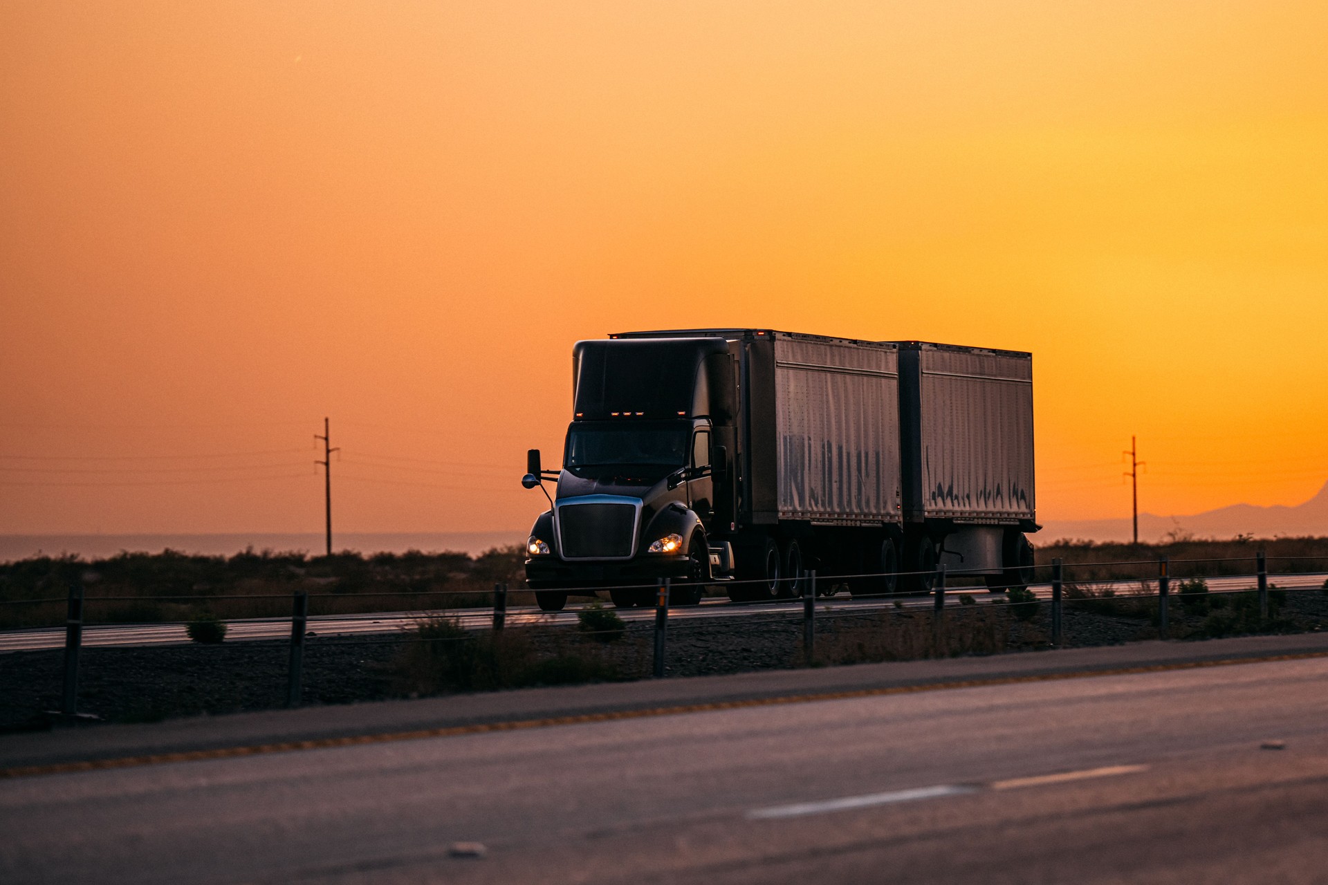 Semi Truck pulling a Double Cargo Trailer "in Tandem" on the Highway in El Paso, Texas with a Vibrant Colored Orange Sunset